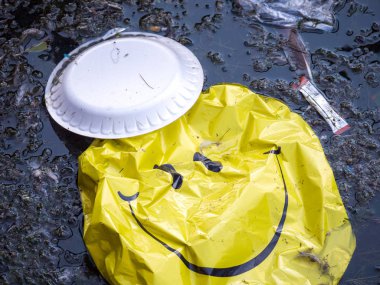 Chicago, Il - 25th Ağustos 2018: Bir sönük sarı gülen yüz balon ve diğer insan olmayan biyobozunur çöp enkaz su üstünde yüzen ve Montrose liman kirletiyor.