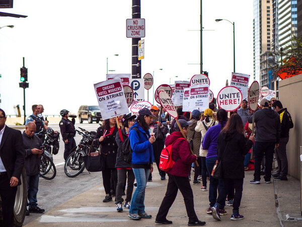 Chicago, IL - September 27th, 2018: Police stand guard as hotel workers picket in front of Hyatt Chicago armed with signs, drums, and noise makers and protesting for better benefits and wages.