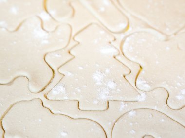 Bir Noel ağacı kesme ve diğer tatil şablonlar veya zencefilli kurabiye adam gibi şekilleri bir closeup ham şeker kurabiye hamuru içinde güzel bir festival arka plan yapma üstüne serpilir un ile kesmek.