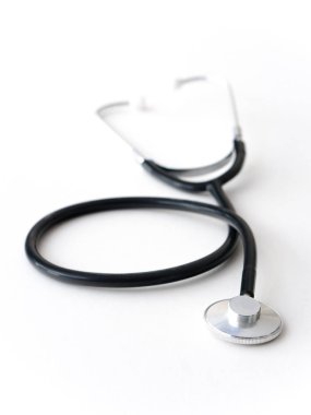 Bir doktor siyah esnek kauçuk ve metal kalp nabzını stetoskop bir beyaz masa üstü izole döşeme çelik.