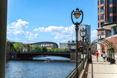 Milwaukee, Wisconsin - May 26th, 2018: The new Milwaukee Bucks Fiserv Forum multi-purpose basketball arena's curved roof rises above nearby buildings adjacent to the Milwaukee River in downtown. clipart