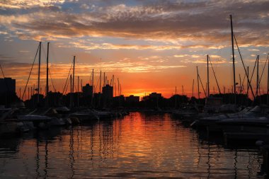 Chicago, Il - 31 Mayıs 2018: Güneş batmadan ufuk üzerinde turuncu renkler bulutların üzerinde üzerinden yayılan ve Montrose liman su üzerinde yansıtan Mayıs ayının son günü.