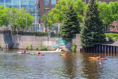 Milwaukee, Wisconsin - 2018 26 Mayıs: İnsanlar bir eğlence gibi kırmızı kürek ve sarı kayaks şehir merkezinde sıcak bahar gününde sakin kahverengi suları Milwaukee Nehri'nin aşağı iyi günler.