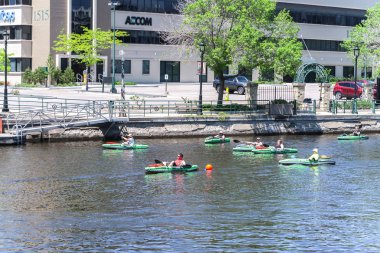Milwaukee, Wisconsin - 26 Mayıs 2018: onlar şişme yeşil kayaks sakin kahverengi suları Milwaukee Nehri'nin aşağı kürek şehir merkezinde bir sıcak bahar sabahı gibi insanlar bir gün eğlence zevk.