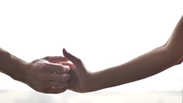 Närbild av en man och kvinna händer och armar med en tumme krig med sina fingrar framför ett fönster med massor av ljusa vita solljus kommer genom glaset. — Stockvideo
