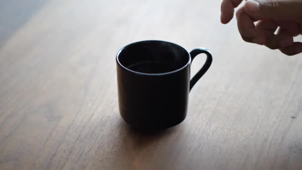 Крупный план, как рука женщины берет горячую чашку чая или кофе из столовой орехового дерева цвета стол с солнечным светом, исходящим из окна за . — стоковое видео