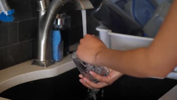 一个混合族的非裔美国妇女在厨房的水槽里洗了洗和冲洗一个玻璃杯, 并把它放在一个白色的塑料晾衣架里. — 图库视频影像