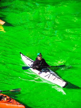 Chicago, IL-16 Mart, 2019: Insanlar şenlikli St. Patrick 's gün giysiler içinde yeşil nehir aşağı kayaklar kürek giymiş yıllık boyama ve kutlama şehir merkezinde sonra yakın bir göz almak için.