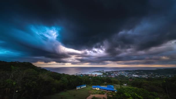 Oscuras nubes turbulentas y dramáticas de tormenta se agitan y giran mientras pasan por encima durante el amanecer sobre el agua y la bahía en Ocho Ríos en la isla de Jamaica . — Vídeos de Stock