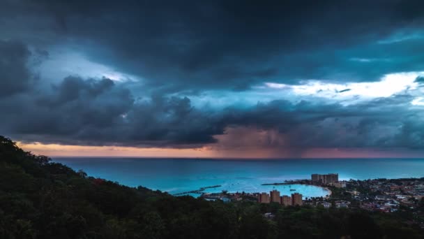 Un lapso de tiempo panorámico de las nubes dramáticas y malhumoradas, el agua y el cielo mientras una tormenta de lluvia rueda fuera del océano sobre la bahía de Ocho Ríos en la isla tropical de Jamaica al caer la noche . — Vídeos de Stock