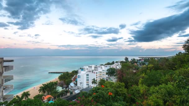 Montego Bay, Jamaika - 24 Mart 2019: Turistler uyanmaya başlarken sessiz ve sakin bir sabahta gün doğumunda S Hotel ve Doctor's Cave Beach'in üzerinden bulutlar geçiyor. — Stok video