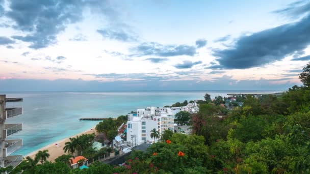 Montego Bay, Jamaica - 24 de marzo de 2019: Las nubes pasan sobre el S Hotel y la playa Doctor 's Cave Beach al amanecer saliendo al mar en una mañana tranquila y tranquila mientras los turistas comienzan a despertar. . — Vídeos de Stock