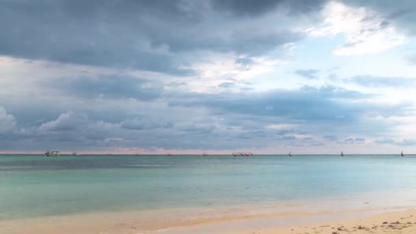 Montego Bay, Jamaica - 23 de marzo de 2019: Turistas y lugareños disfrutan de una hermosa velada descansando en la arena y nadando en el tranquilo agua en la playa Deadend Buccaneer antes del atardecer mientras las nubes pasan por encima . — Vídeos de Stock