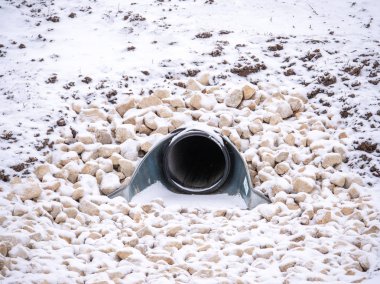 Büyük bir yağmur suyu drenaj menfez borusu bir tutma gölet taş veya çakıl içinde kar kırsal Wisconsin kırsal wisconsin peyzaj kapsayan kış sezonunda ayarlanmış içine boşaltma bir closeup görünümü.