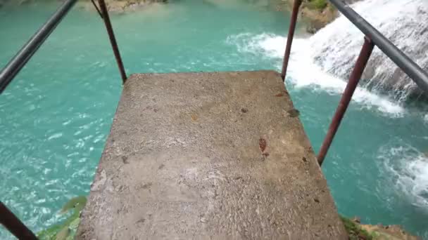 Caminhando para baixo e olhando para a borda da plataforma de salto com vista para a cachoeira inclinada popular e piscina abaixo na bela cachoeira Cool Blue Hole e piscinas naturais em Ocho Rios Jamaica — Vídeo de Stock