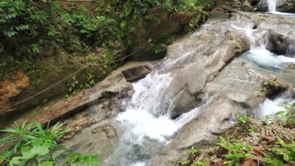 Μια εντυπωσιακή θέα στον ποταμό των κλιμακωτών καταρρακτών και των τροπικών φυσικών λιμνών στο πανέμορφο τουριστικό αξιοθέατο της δροσερής γαλάζιας τρύπας στο Ότσο Ρίος Τζαμάικα με πλούσια βλάστηση στο ποτάμι — Αρχείο Βίντεο