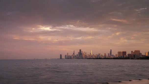 シカゴ 2019年7月4日 群衆は7月4日を祝うためにモントローズ港の近くにミシガン湖に沿って集まり 劇的な雲の頭上で街のスカイラインに沈む太陽を見ます — ストック動画