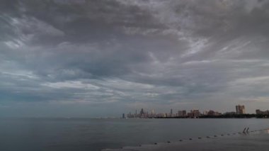 Chicago, Il - 4 Temmuz 2019: Montrose Limanı yakınlarındaki Michigan Gölü'nde toplanan kalabalıklar, 4 Temmuz'u kutlamak ve bazı insanlar yüzmek için suya atlayırken şehrin siluetinde güneşin batışını izliyorlar..