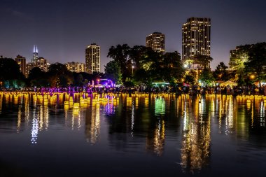 Chicago, Il - 20 Temmuz 2019: Lincoln Park Cumartesi günü Su Fener festivalinde lagün boyunca parlayan fenerler gıda, müzik ve eğlence bir gece için fon olarak şehir silueti ile yüzer.