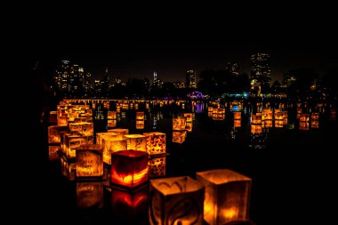 Chicago, Il - 20 Temmuz 2019: Lincoln Park Cumartesi günü Su Fener festivalinde lagün boyunca parlayan fenerler gıda, müzik ve eğlence bir gece için fon olarak şehir silueti ile yüzer.