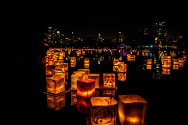 Chicago, Il - 20 Temmuz 2019: Lincoln Park Cumartesi günü Su Fener festivalinde lagün boyunca parlayan fenerler gıda, müzik ve eğlence bir gece için fon olarak şehir silueti ile yüzer.