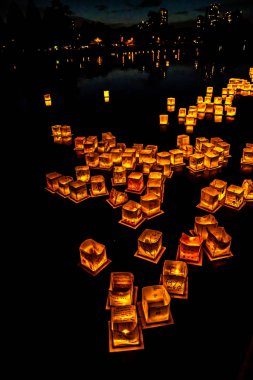 Chicago, Il - 20 Temmuz 2019: Lincoln Park'taki Water Lantern Festivali'nde Cumartesi akşamı müzik, yemek ve aile dostu etkinliklerle parlayan turuncu fenerler Güney Lagünü boyunca süzülüyor.