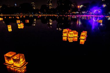 Chicago, Il - 20 Temmuz 2019: Lincoln Park'taki Water Lantern Festivali'nde Cumartesi akşamı müzik, yemek ve aile dostu etkinliklerle parlayan turuncu fenerler Güney Lagünü boyunca süzülüyor.