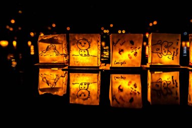Chicago, Il - 20 Temmuz 2019: Lincoln Park'taki Water Lantern Festivali'nde Cumartesi akşamı müzik, yemek ve aile dostu etkinliklerle parlayan turuncu fenerler Güney Lagünü boyunca süzülüyor.