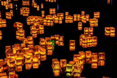 Chicago, Il - 20 Temmuz 2019: Lincoln Park'taki Water Lantern Festivali'nde Cumartesi akşamı müzik, yemek ve aile dostu etkinliklerle parlayan turuncu fenerler Güney Lagünü boyunca süzülüyor.