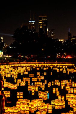 Chicago, Il - 20 Temmuz 2019: Lincoln Park Cumartesi günü Su Fener festivalinde lagün boyunca parlayan fenerler gıda, müzik ve eğlence bir gece için fon olarak şehir silueti ile yüzer.