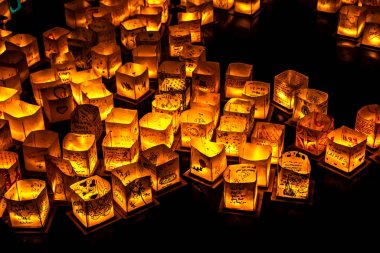 Chicago, Il - 20 Temmuz 2019: Lincoln Park'taki Water Lantern Festivali'nde Cumartesi akşamı müzik, yemek ve aile dostu etkinliklerle parlayan turuncu fenerler Güney Lagünü boyunca süzülüyor.