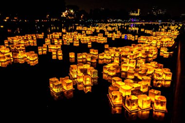 Chicago, Il - 20 Temmuz 2019: Lincoln Park'taki Water Lantern Festivali'nde Cumartesi akşamı müzik, yemek ve aile dostu etkinliklerle parlayan turuncu fenerler Güney Lagünü boyunca süzülüyor.