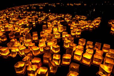 Chicago, Il - 20 Temmuz 2019: Lincoln Park'taki Water Lantern Festivali'nde Cumartesi akşamı müzik, yemek ve aile dostu etkinliklerle parlayan turuncu fenerler Güney Lagünü boyunca süzülüyor.