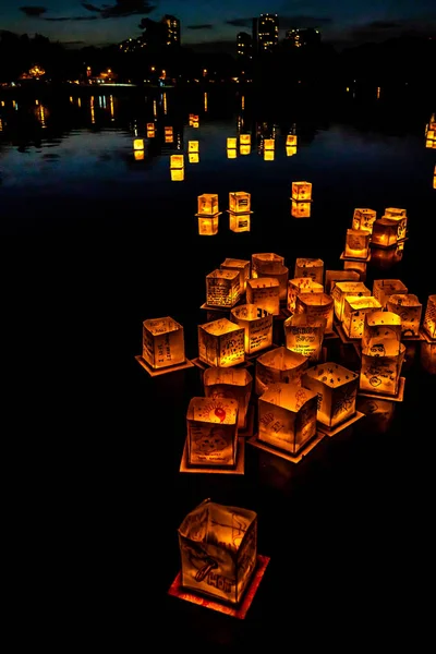 Chicago, Il - 20 Temmuz 2019: Lincoln Park'taki Water Lantern Festivali'nde Cumartesi akşamı müzik, yemek ve aile dostu etkinliklerle parlayan turuncu fenerler Güney Lagünü boyunca süzülüyor.
