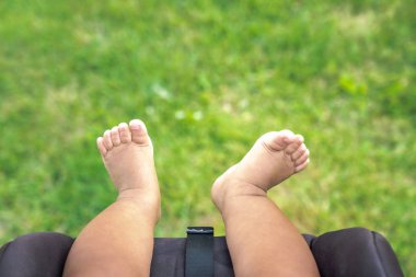 O yaz onun araba koltuğu bebek arabası oturur gibi bir parkta çim üzerinde temiz havaya asılı karışık bir ırk bebek bebek çıplak deri tombul bacaklar, ayak ve ayak.