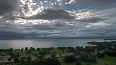Chicago, Il - 6 Ağustos 2019: Michigan Gölü üzerinde fırtına bulutları ufukta geçerken ve güneş parlamaya başlarken Lake Shore Drive'da trafik ilerliyor.