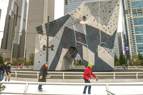 Чикаго, штат Иллинойс - 25 января 2016 года: Люди катаются на коньках по ленте в парке Мэгги Дэйли рядом с парком Миллениум в центре города в холодный зимний день, когда они проходят мимо скалолазания на центральном льду
.