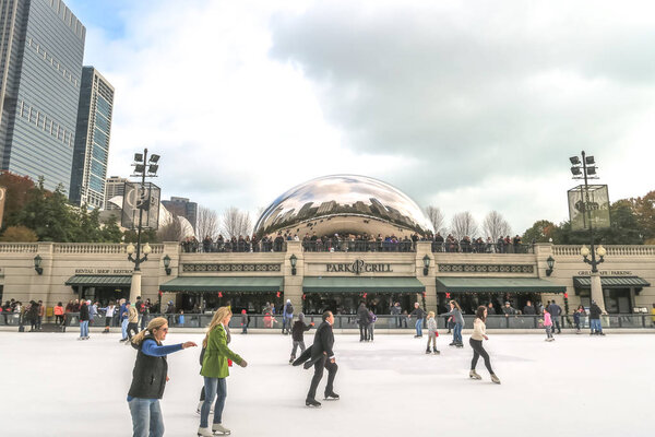 Chicago, IL - January 25th, 2016: People gather by the Cloud Gate sculpture overlooking the ice rink  to watch ice skaters near Park Grill in Millennium Park in downtown Chicago.
