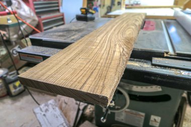 Endüstriyel bir masada oturan bir levha veya zebrawood tahta parçası yakın bir bakış açısı bıçak kaldırdı ile bir ahşap atölyesinde gördüm.