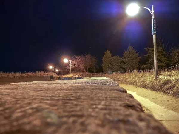 Уличная Лампа Освещает Бетонную Дорожку Покрытую Песком Прилегающим Большим Каменным — стоковое фото