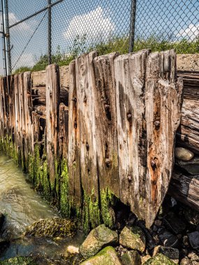 Yukarıda chainlink çit ile Doğu Nehri boyunca yıpranmış ahşap plakalar.