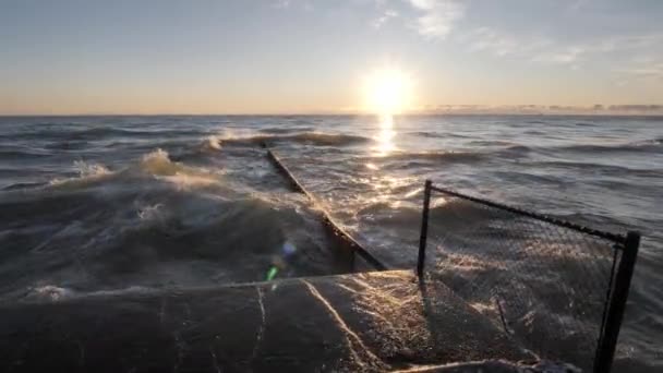 Clip de paysage marin à mouvement lent du soleil réfléchissant sur l'eau et barrière de rivage en béton humide alors que les vagues s'écrasent, entrent en collision et éclaboussent dans un tas de tôles d'acier ondulé et les unes aux autres . — Video