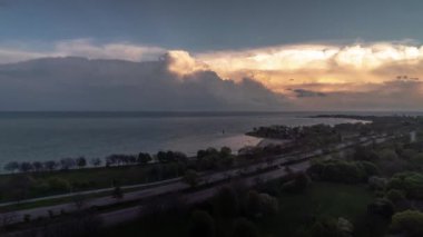 Bulutlar pembe ve turuncu renge dönüşmeye başladığında Chicago 'daki mavi gökyüzünde Michigan Gölü ve Shore Yolu' nun suları üzerinde bulutlu hava bulutlu bir zaman çizelgesi oluşturuyor..