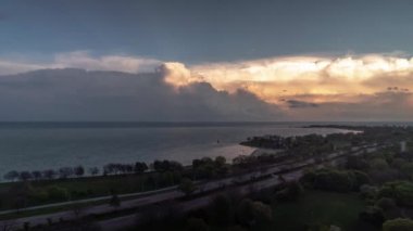 Hava bulutlu bulutlu gökyüzü, Michigan Gölü ve Şikago 'daki Lake Shore Yolu' nun suları üzerinde gün batımında bulutlar pembe ve turuncu renklere dönüşmeye başladığında,.