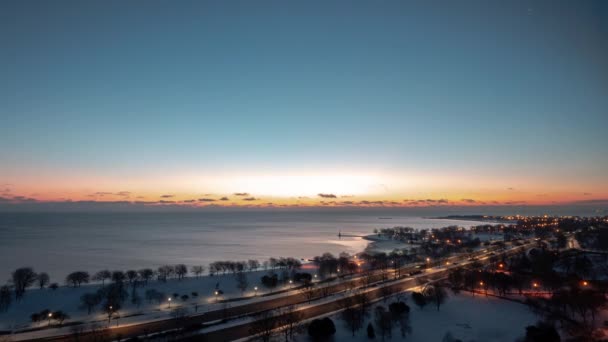 Beautiful aerial morning sunrise timelapse of the Chicago Lakefront along Lake Michigan with traffic passing by on Lake Shore Drive as night turns to day as the sun comes up over clouds on the horizon — Stock Video