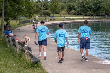 Chicago, IL - 23 Haziran 2020: İnsanların COVID-19 'un ortasında toplanmasını önlemek için Chicago Park Bölgesi devriyesinden mavi tişört giyen genç yetişkinler.