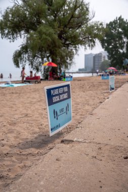 Chicago, IL - 28 Haziran 2020: Loyola sahilindeki sosyal mesafe tabelaları kapalı kalan plajlara rağmen COVID-19 Coronavirus salgını sırasında insanların toplandığı gibi.