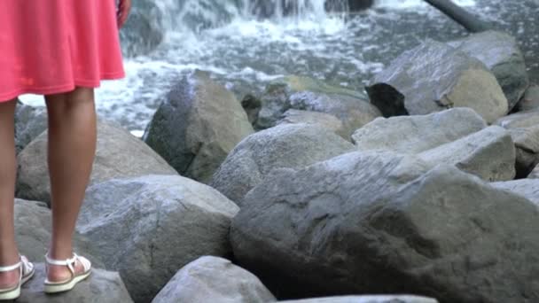 Şelalenin Önündeki Kayanın Üzerinde Duran Beyaz Kemerli Sandaletler Pembe Etekli — Stok video