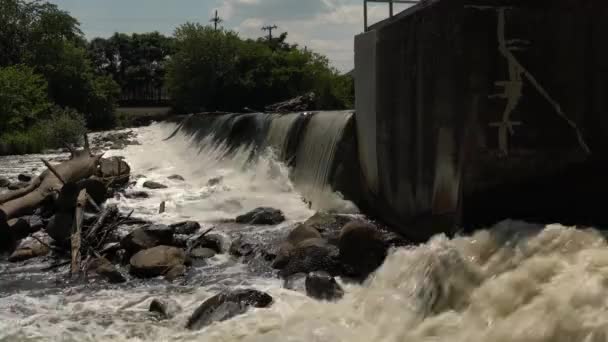 下の川にコンクリートダムを作った男の上を流れる滝の流れやカスケード水の側面のビューをパンニング — ストック動画