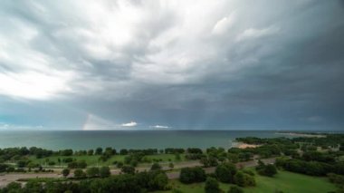Chicago, IL - 2 Ağustos 2020: Michigan Gölü üzerinde bir yaz fırtınasının ardından gökkuşağı gökyüzünde beliriyor ve trafik Lake Shore Drive 'dan geçerken güneş parlamaya başlıyor.